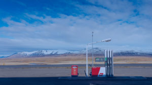 Mountain with snow on the background with gas pump in front on an empty road